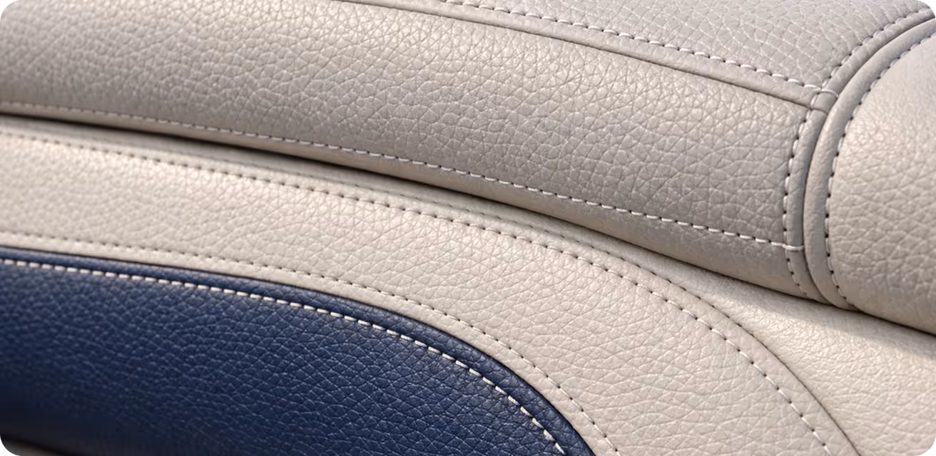 Close-up of textured leather upholstery with gray and dark blue sections and visible stitching.