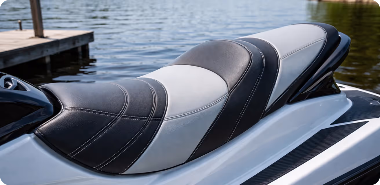 Close-up of a black and white cushioned seat on a white personal watercraft by a dock.