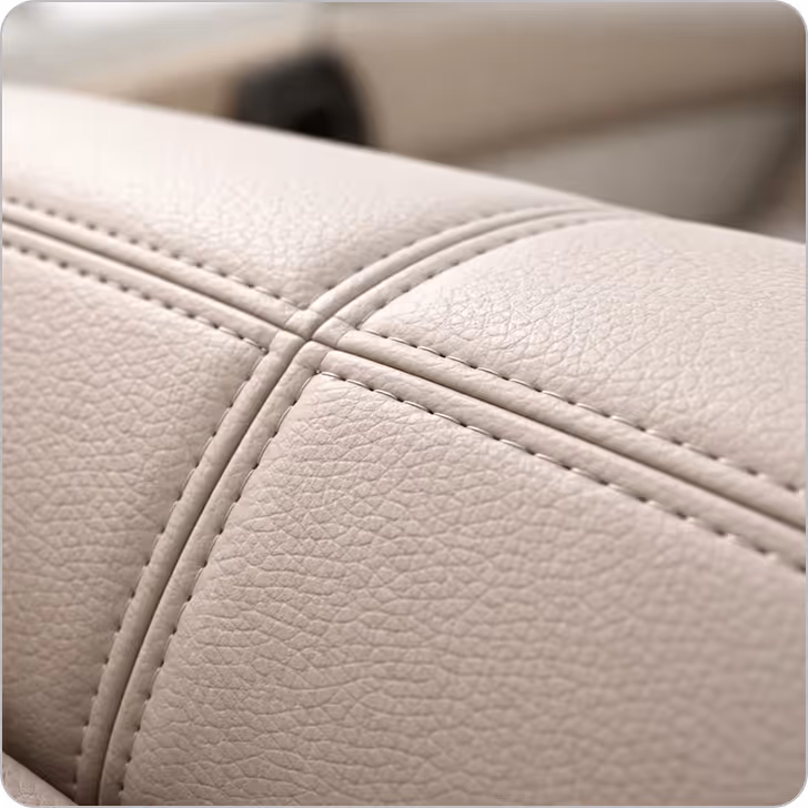 Close-up of beige leather upholstery with visible stitching and texture.