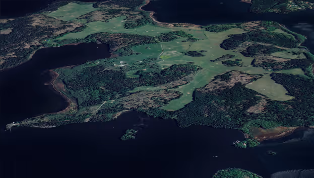 Flygbild av skogslandskap med sjöar, grönska och mörka vattenområden omgivna av skog.