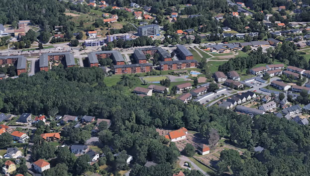 Flygfoto över ett europeiskt bostadsområde med villor, lägenheter och gröna träd.