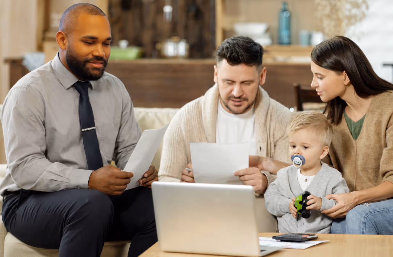 Insurance agent John Caraballo reviewing coverage documents with a young family at home, helping parents plan protection for their child and household.