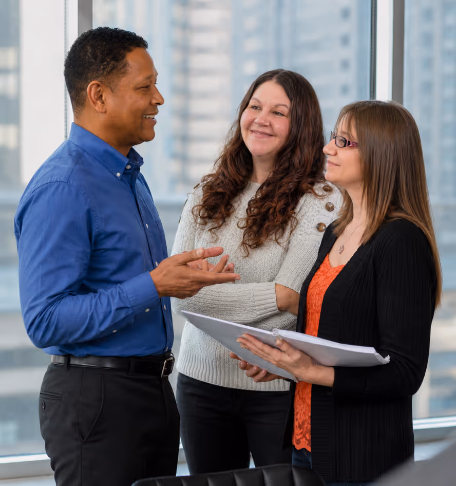 Anthony Givens, Nicole Vuittonet, and Shantell Combs reviewing office documents together in a professional insurance agency workspace.
