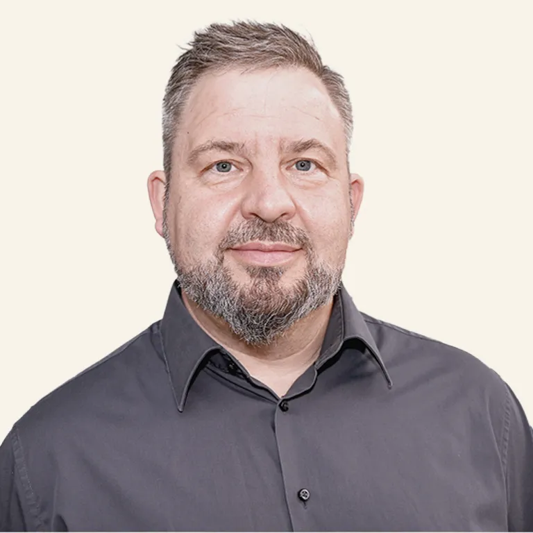 Porträtfoto von Jörg Hohmeier, A+H Meyer. Er trägt ein dunkles Hemd und er lächelt leicht in die Kamera. 
Der Hintergrund ist hell und neutral.