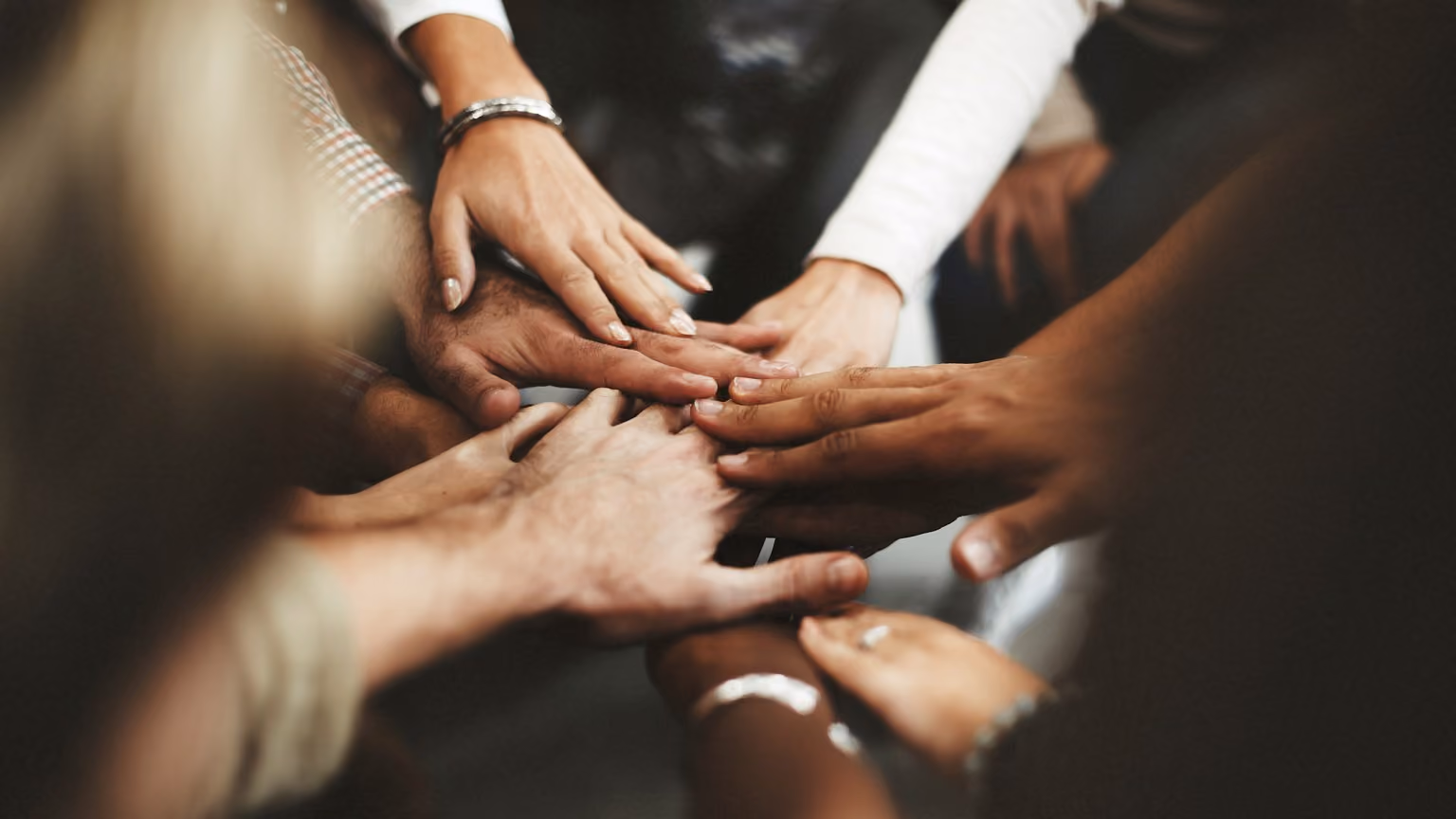 Multiple hands stacked together symbolizing teamwork and unity.