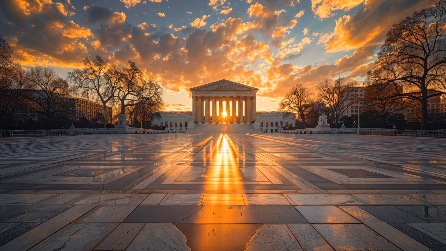 Sunset shining through columns of a classical government building reflecting on polished plaza tiles.