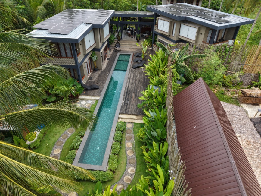 Vue aérienne d'Islaya Villas à Siargao, aux Philippines, mettan en valeur les villas, la piscine et la végétation tropicale environnante, réalisée par drone par Alpine Aerial.