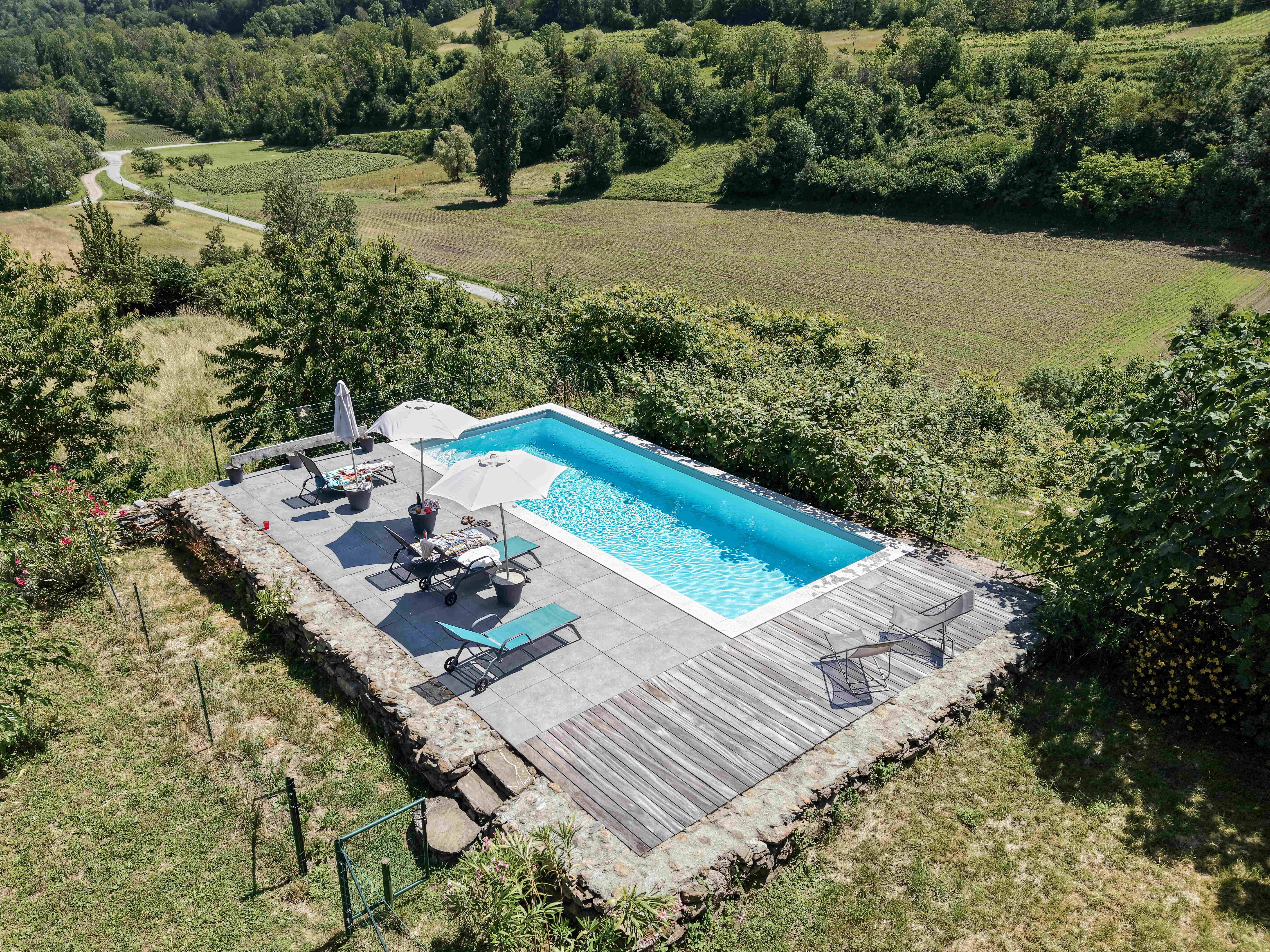 Vue aérienne de la piscine extérieure aménagée au coeur d'un environnement verdoyant et paisible.