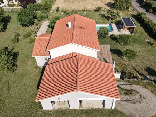 Vue arienne en plongée de la maison, de ses toitures et de ses espaces extérieurs.