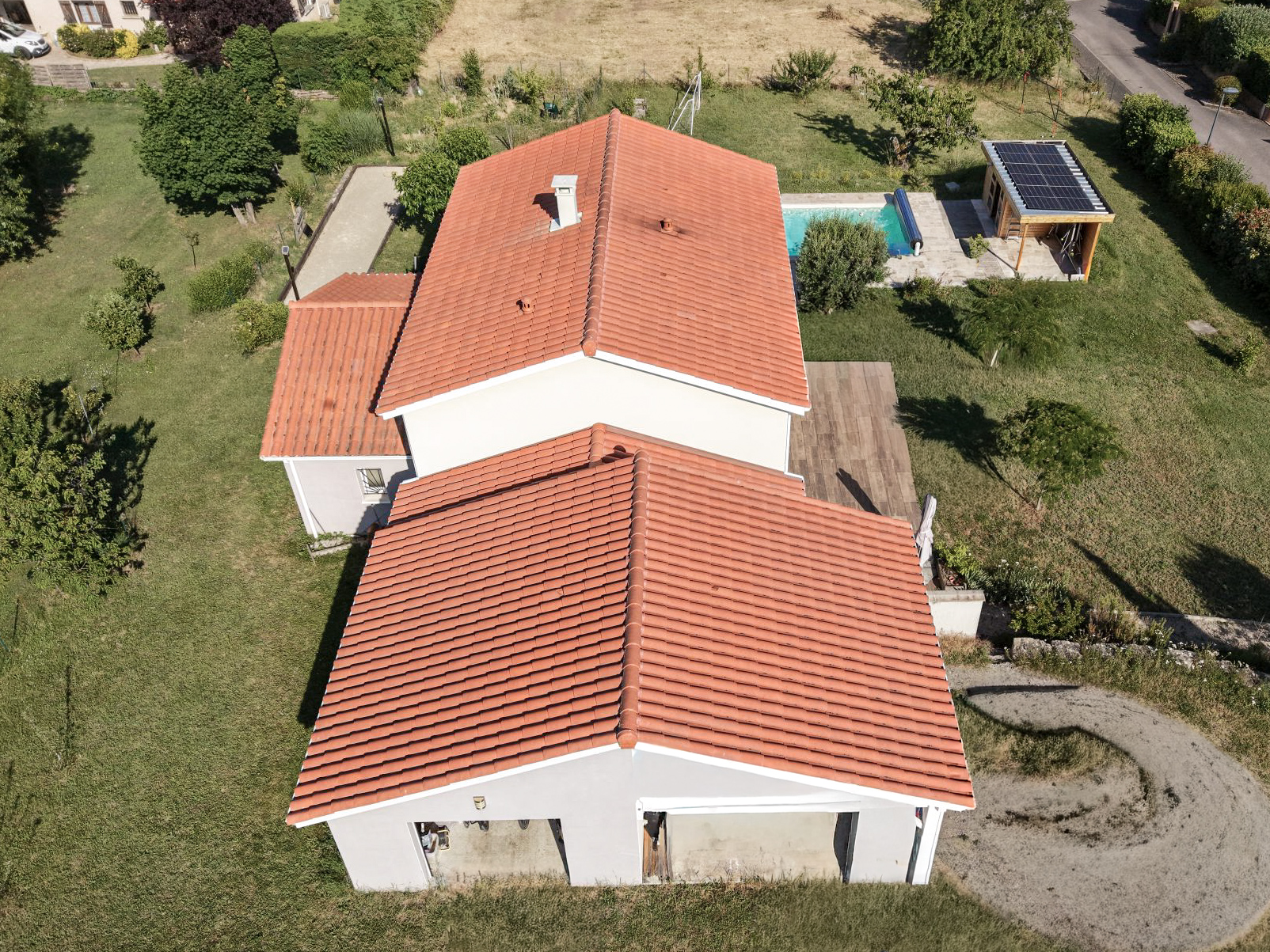 Vue arienne en plongée de la maison, de ses toitures et de ses espaces extérieurs.