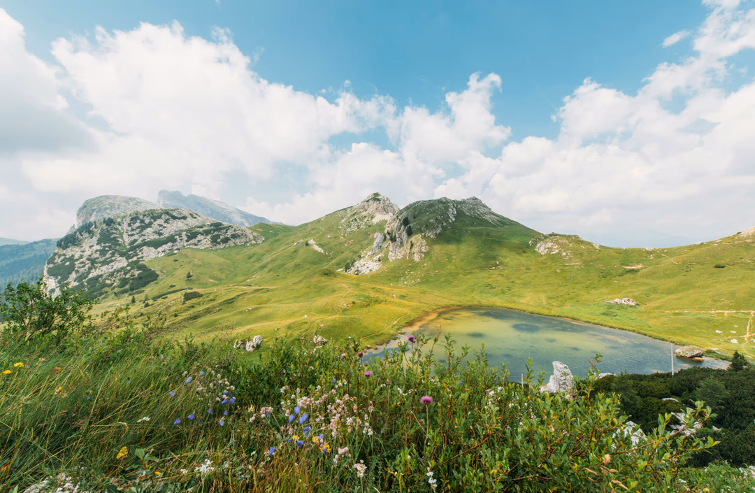 Grüne Berglandschaft mit kleinem See unter Wolkenhimmel – Symbolbild für langfristige Altersvorsorge