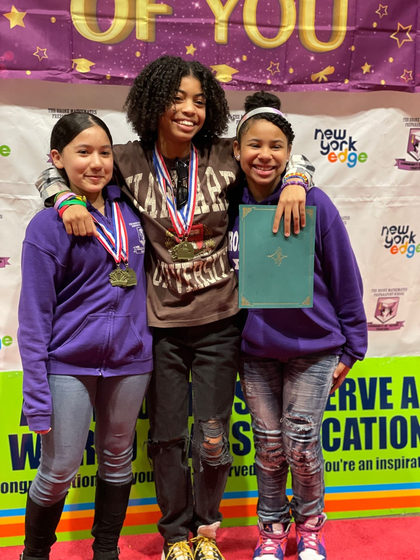 Three students posing with medals and award at Bronx Math competition
