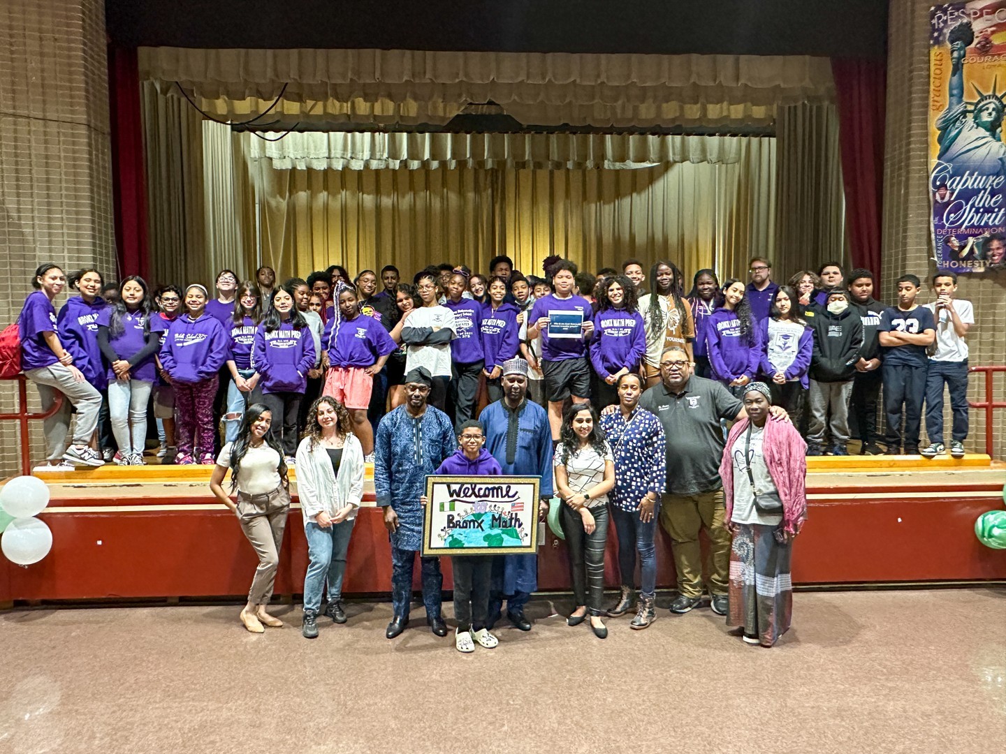 Bronx Math students and staff posing together on school auditorium stage
