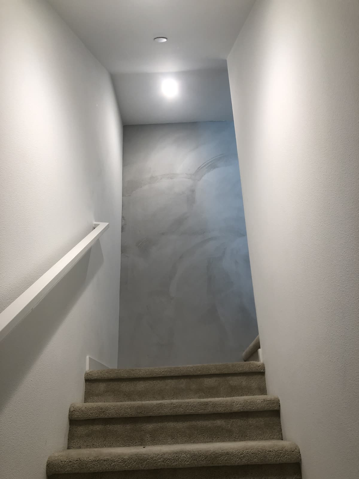Blue grey troweled plaster feature wall at the top of a stairwell