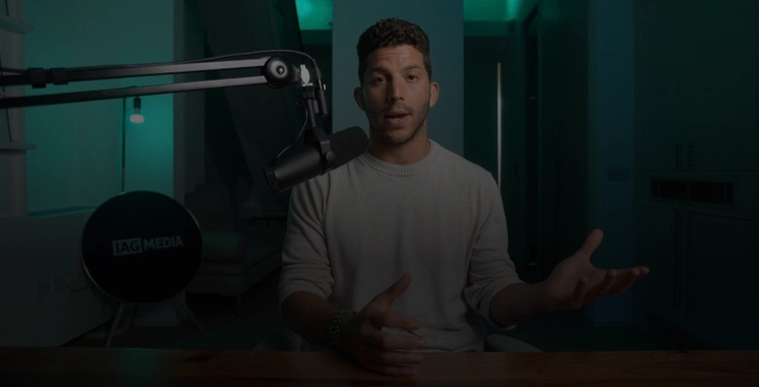 Josh speaking into a microphone in a dimly lit room with teal lighting.