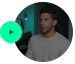 Josh with short dark hair and beard wearing a beige shirt, speaking in a dimly lit room with a green play button overlay.