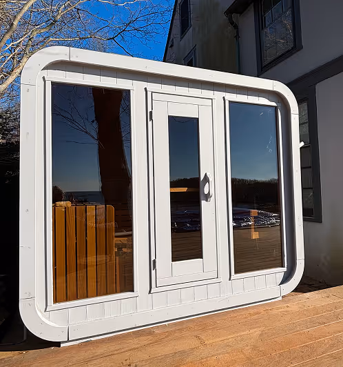 Modern white-framed large window with a central door reflecting outdoor scenery and wooden deck.