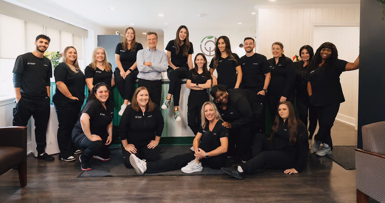 Group of diverse healthcare professionals in black uniforms smiling together in a bright, modern office setting.