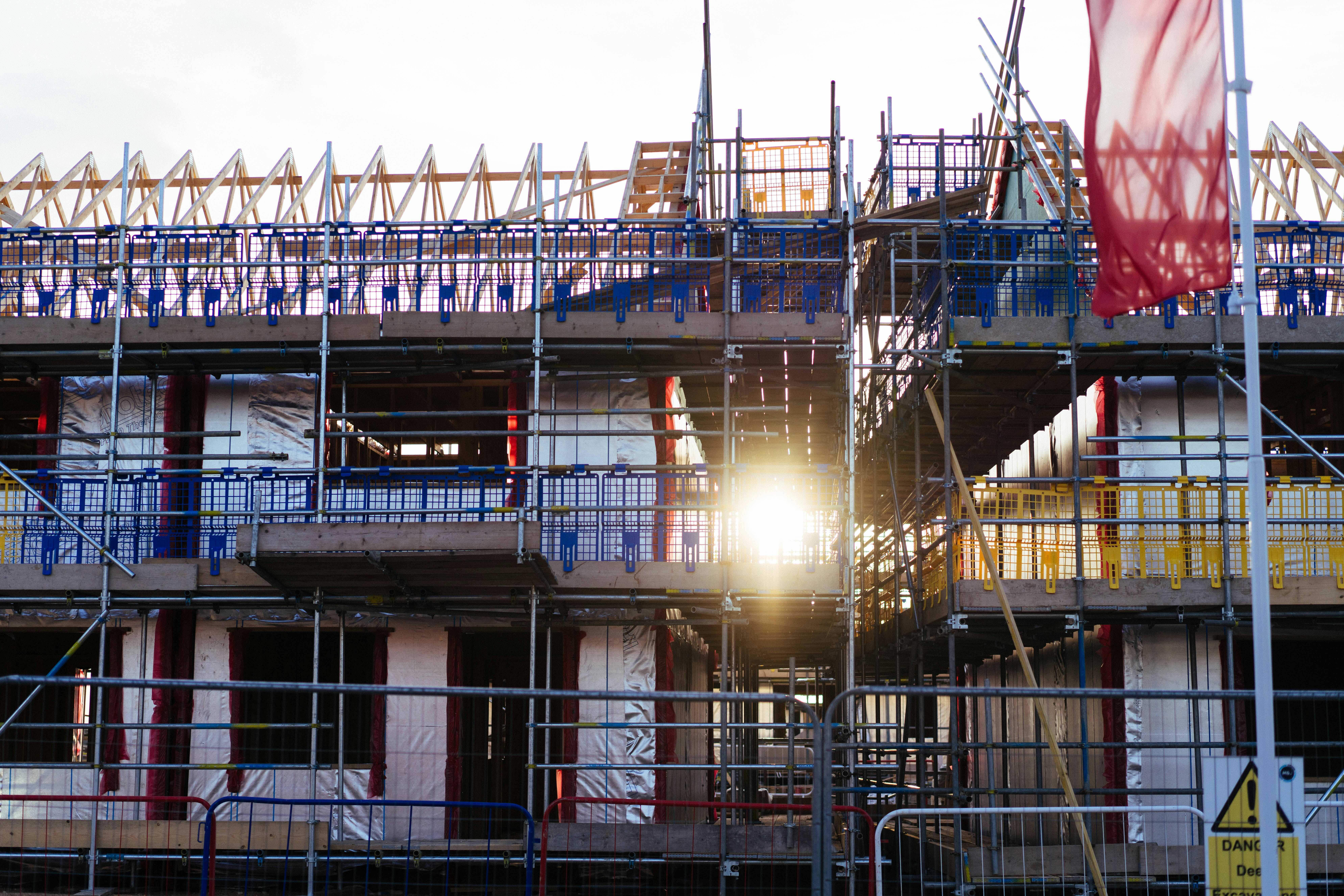 Sunlight shining through scaffolding at a building construction site with exposed framing.