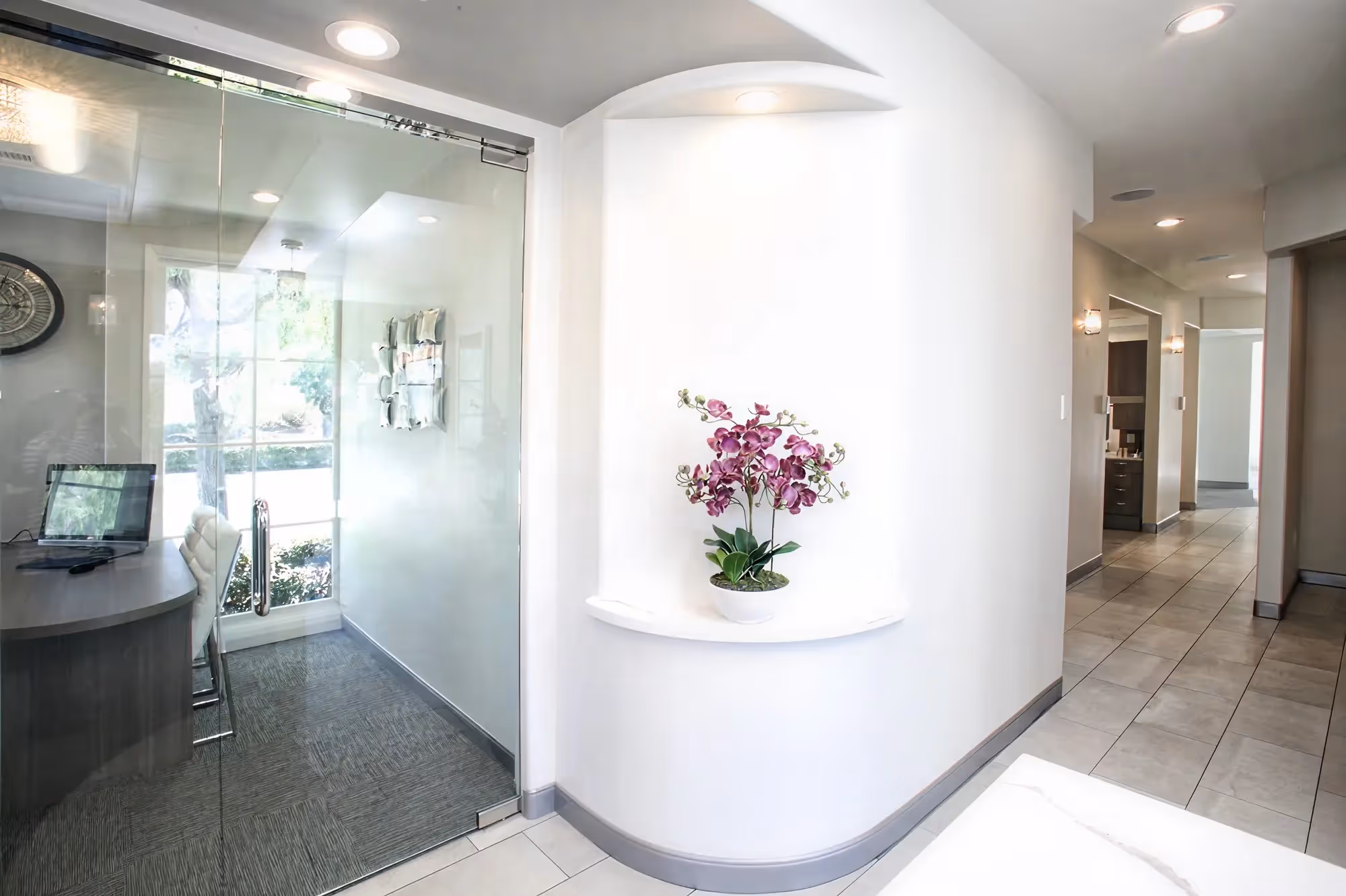 Interior entrance at Ortega Cottage Dentistry with orchid in arched wall niche and frosted glass entry door
