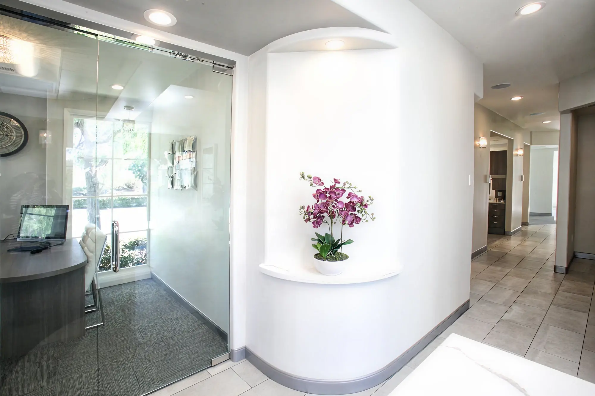 Interior entrance at Ortega Cottage Dentistry with orchid in arched wall niche and frosted glass entry door
