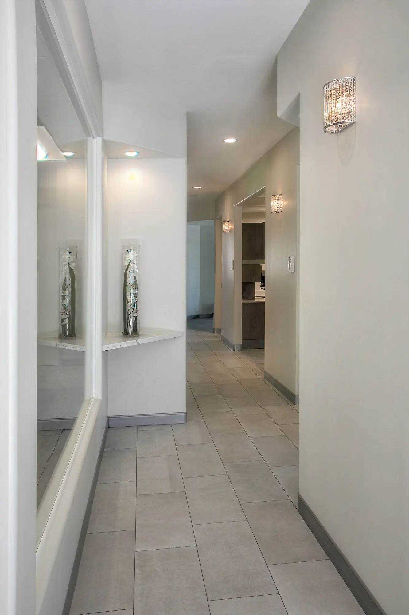 Clean hallway with crystal wall sconces and patient rinse station leading to treatment rooms at Ortega Cottage Dentistry