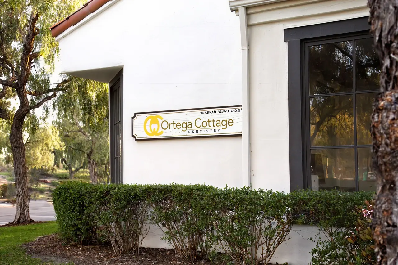 Exterior signage of Ortega Cottage Dentistry on the white cottage building in San Juan Capistrano