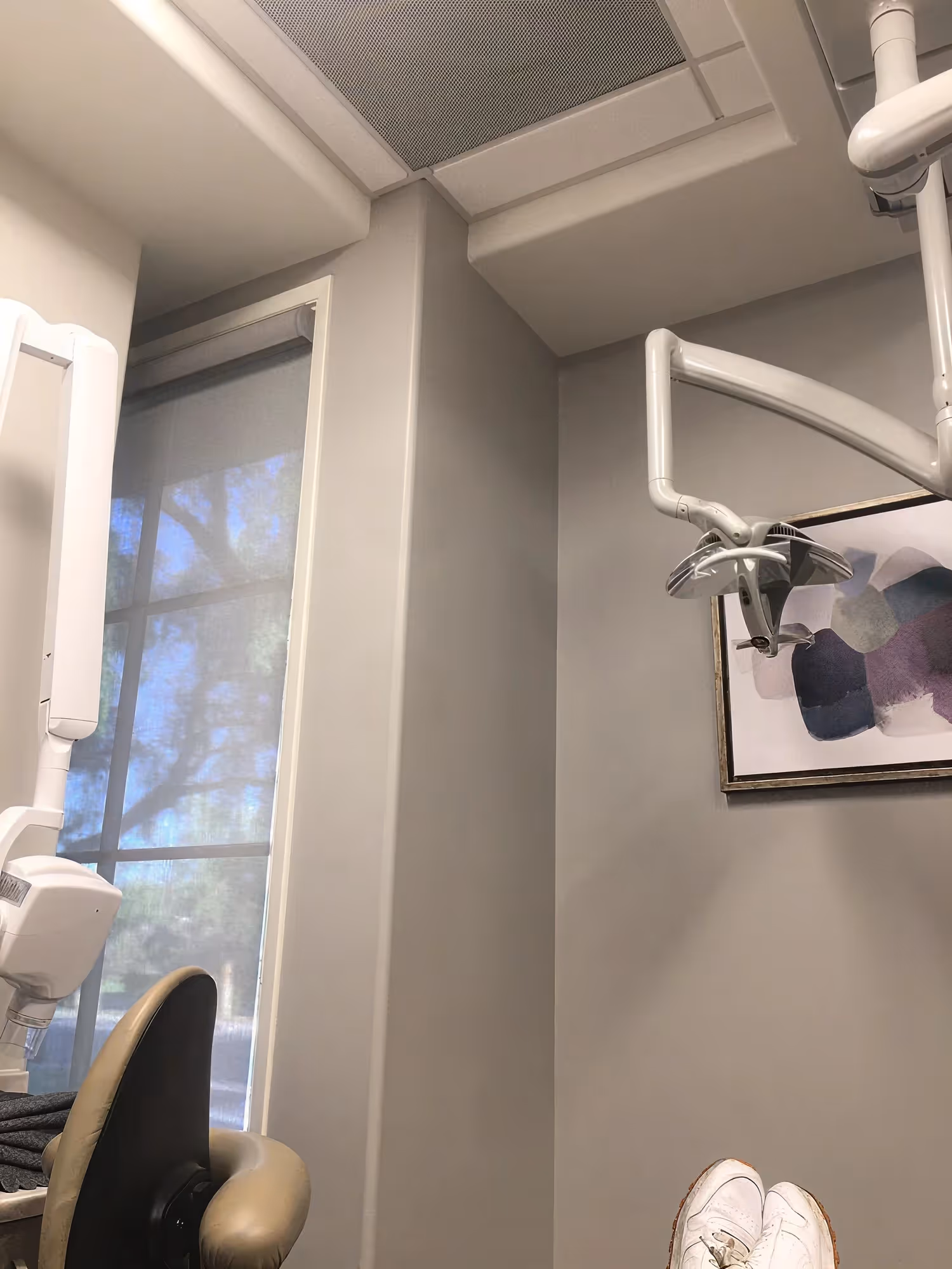 Dental treatment room at Ortega Cottage Dentistry with overhead operatory light, window view, and abstract wall art
