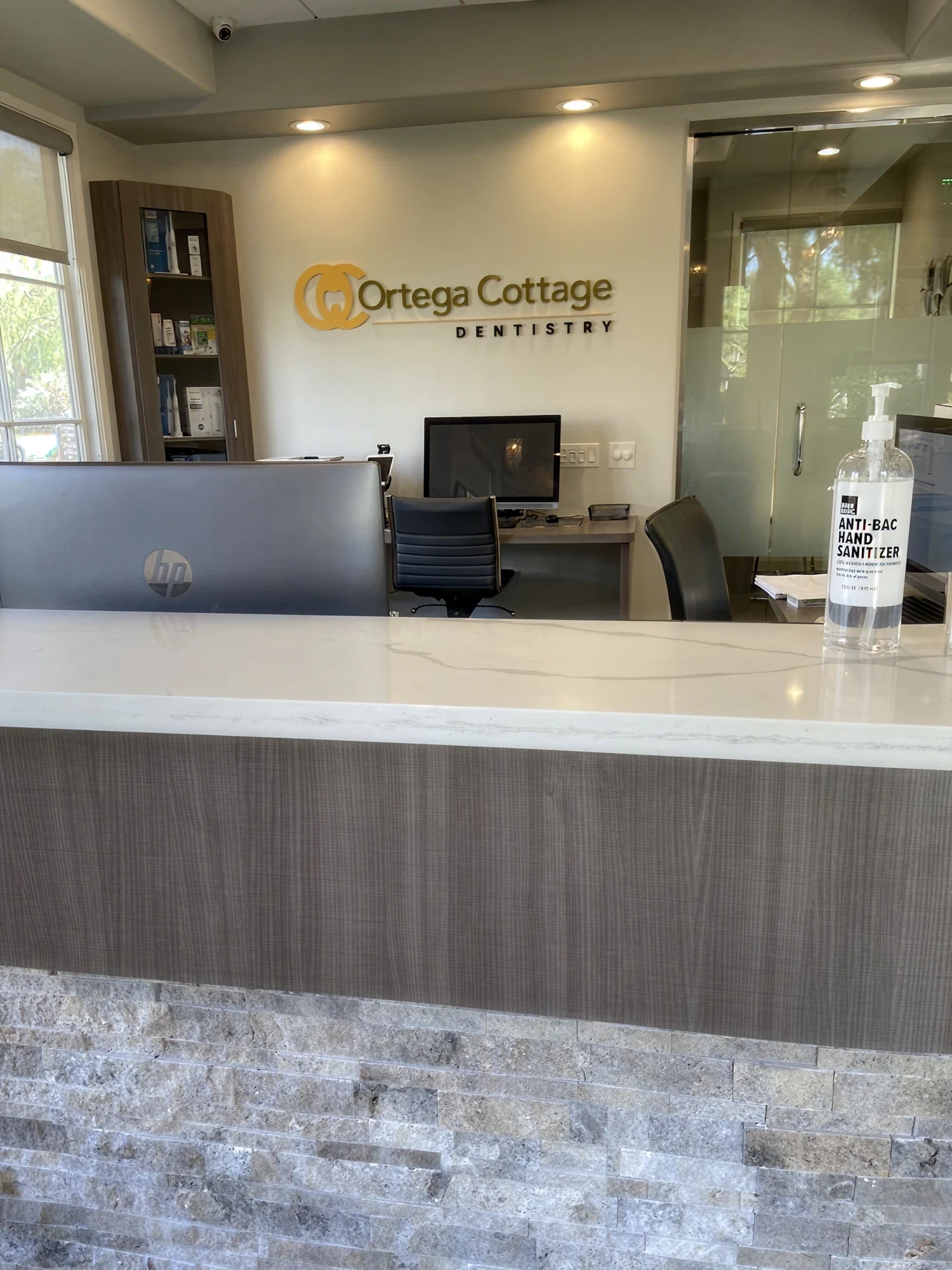Ortega Cottage Dentistry front desk with stone accent counter, HP workstations, and branded logo wall