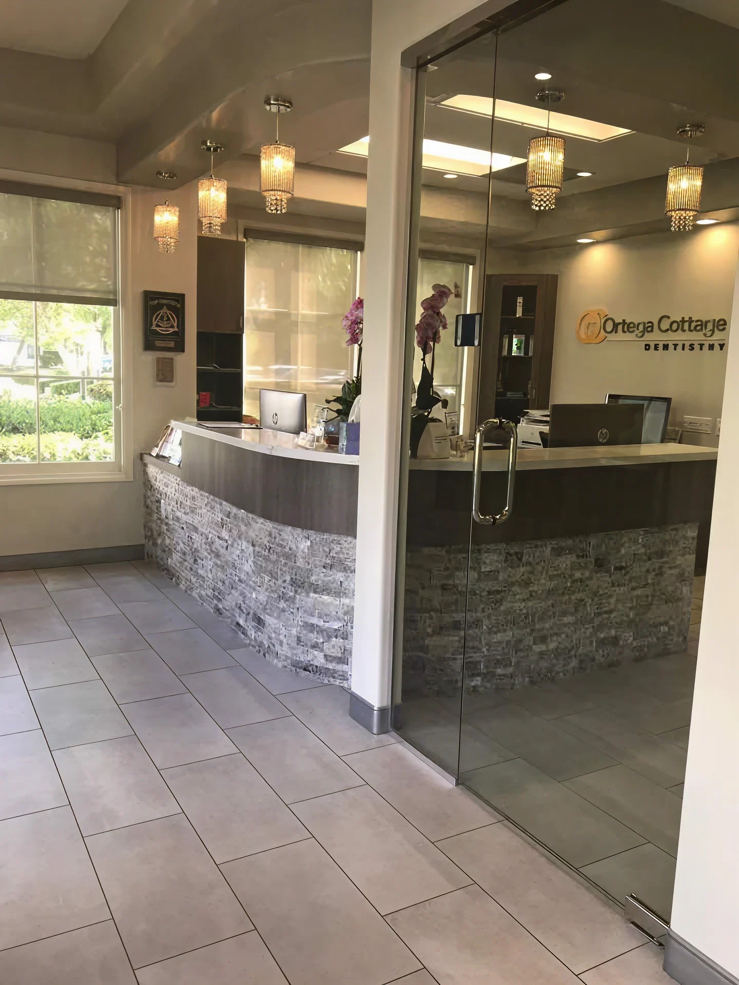 Reception area at Ortega Cottage Dentistry viewed through the glass entry door with crystal pendant lighting