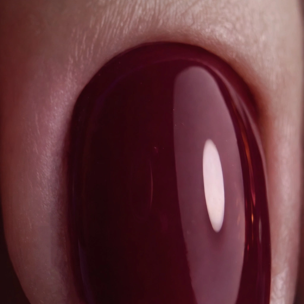 Gros plan sur une pierre précieuse ovale, de couleur violet foncé et polie, tenue entre les doigts.