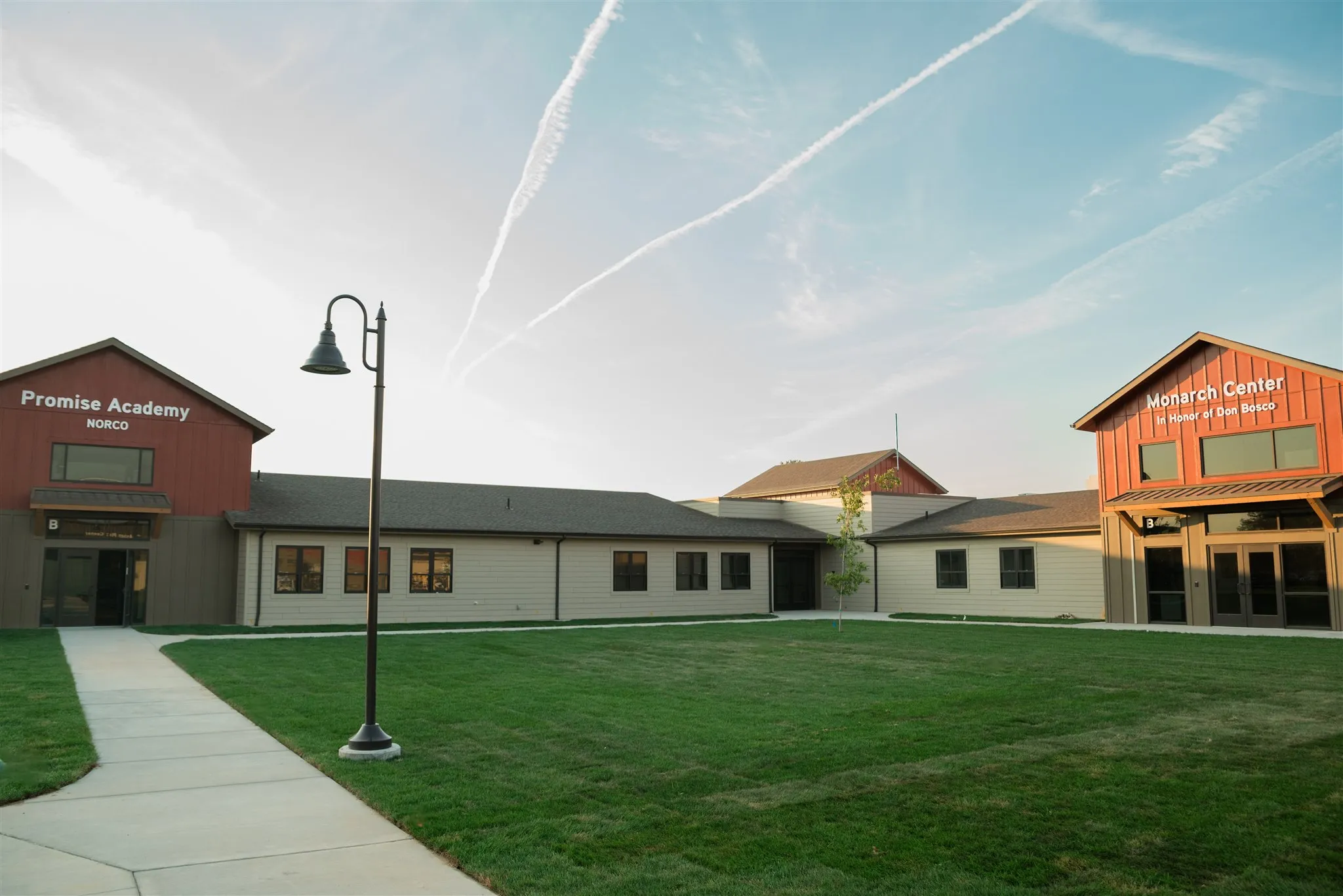 Promise Academy Norco and Monarch Center buildings with green lawn and lamp post under a blue sky.