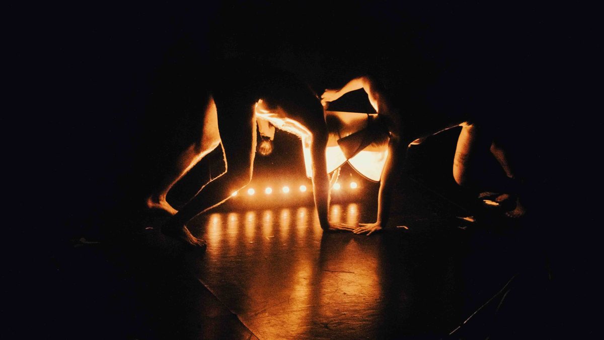 Two dancers arched in silhouette against warm backlight in Glamour Magique's Le debut des yeux