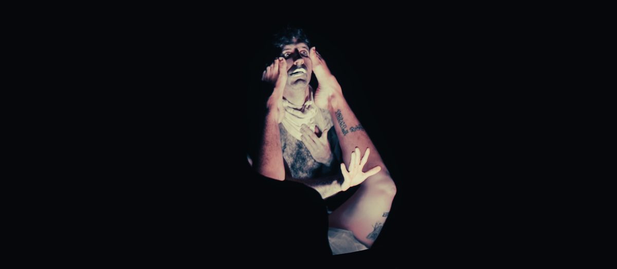 A distressed face projected onto a performer's body, hand raised