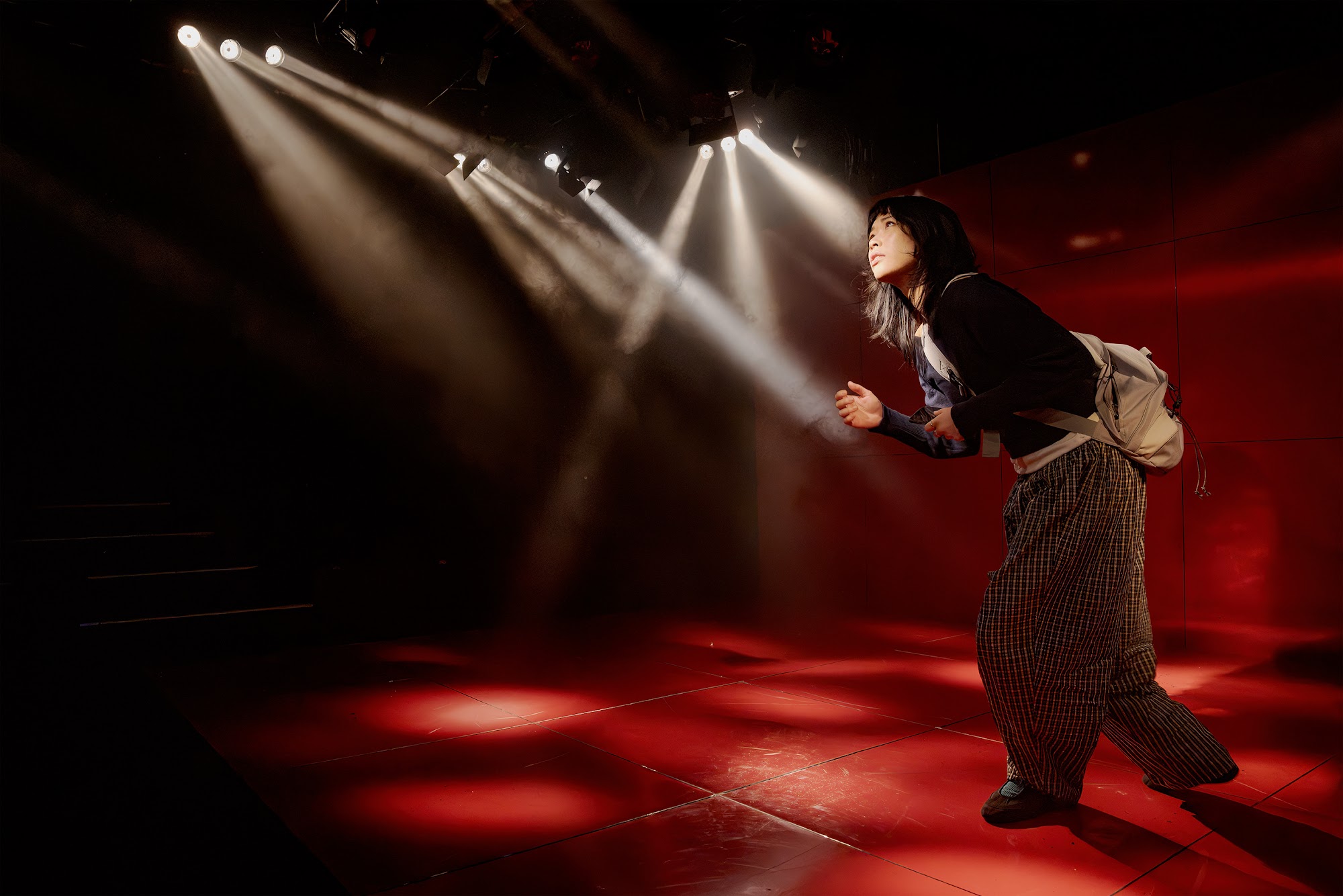 Claudia is in motion, appearing to seek something, while beams of light shine around her.