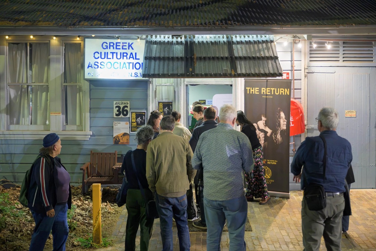 People gather outside the Greek Theatre, waiting in a line to enter the venue.