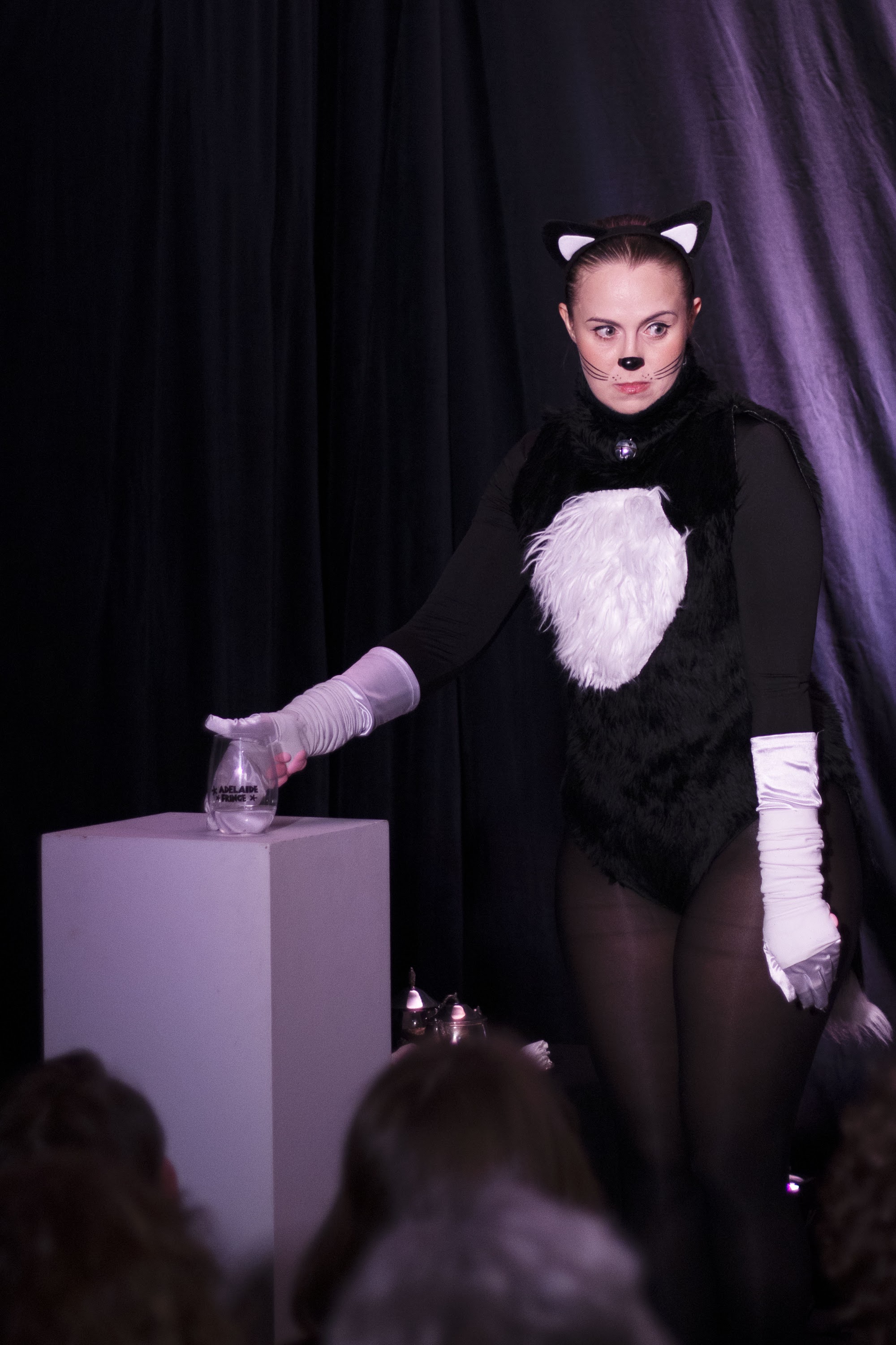 A woman dressed as a cat threatening to push a glass over.