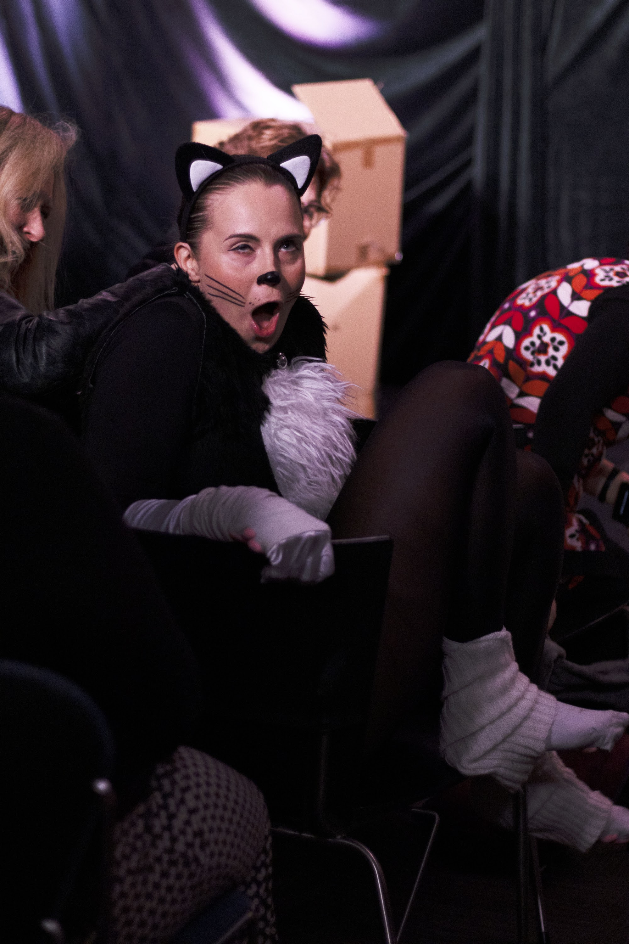 A woman dressed as a cat moaning in ecstasy as an audience member scratches her neck.