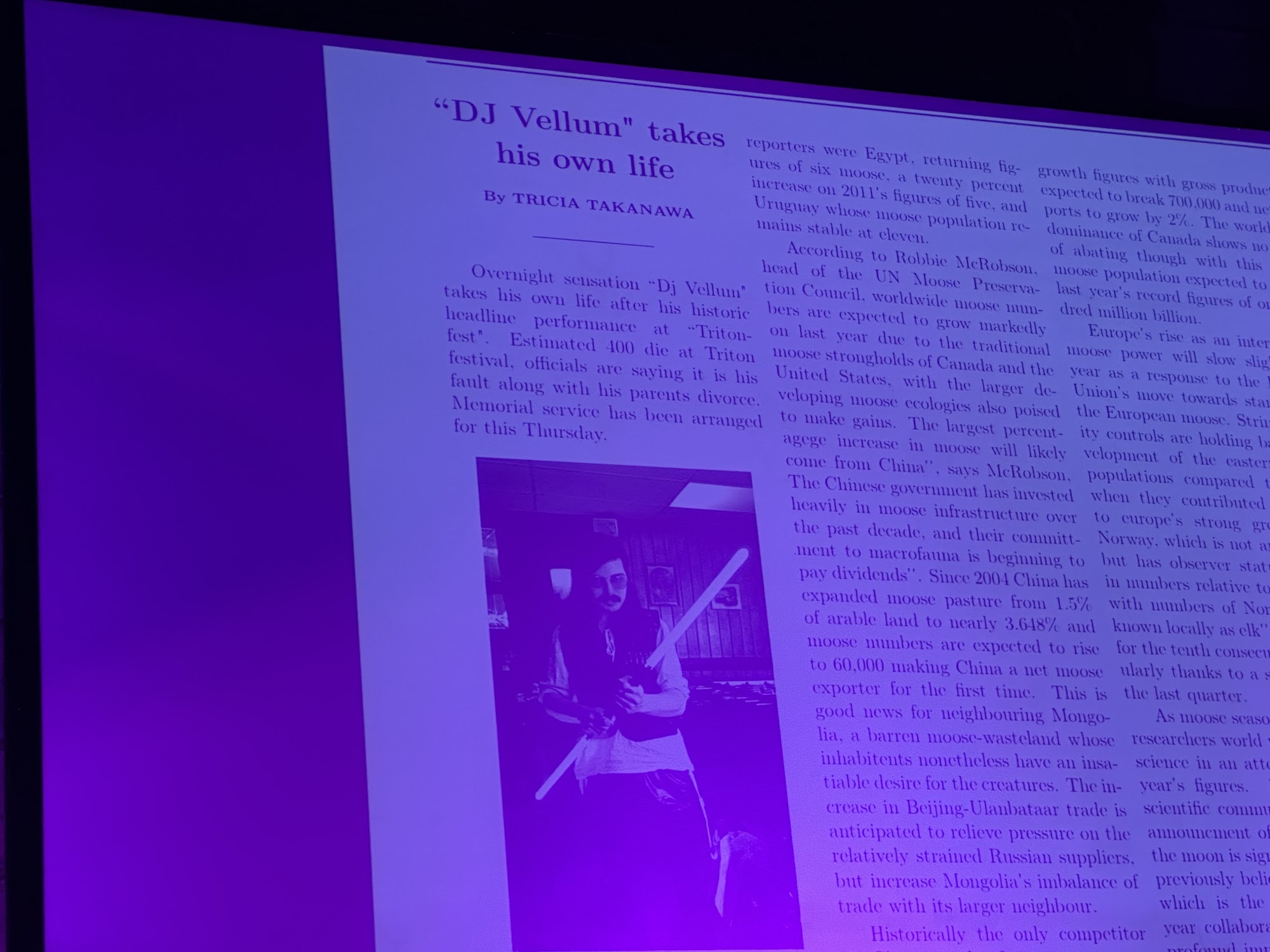 A newspaper clipping headlined DJ Vellum takes his own life projected onto a large screen above the stage.