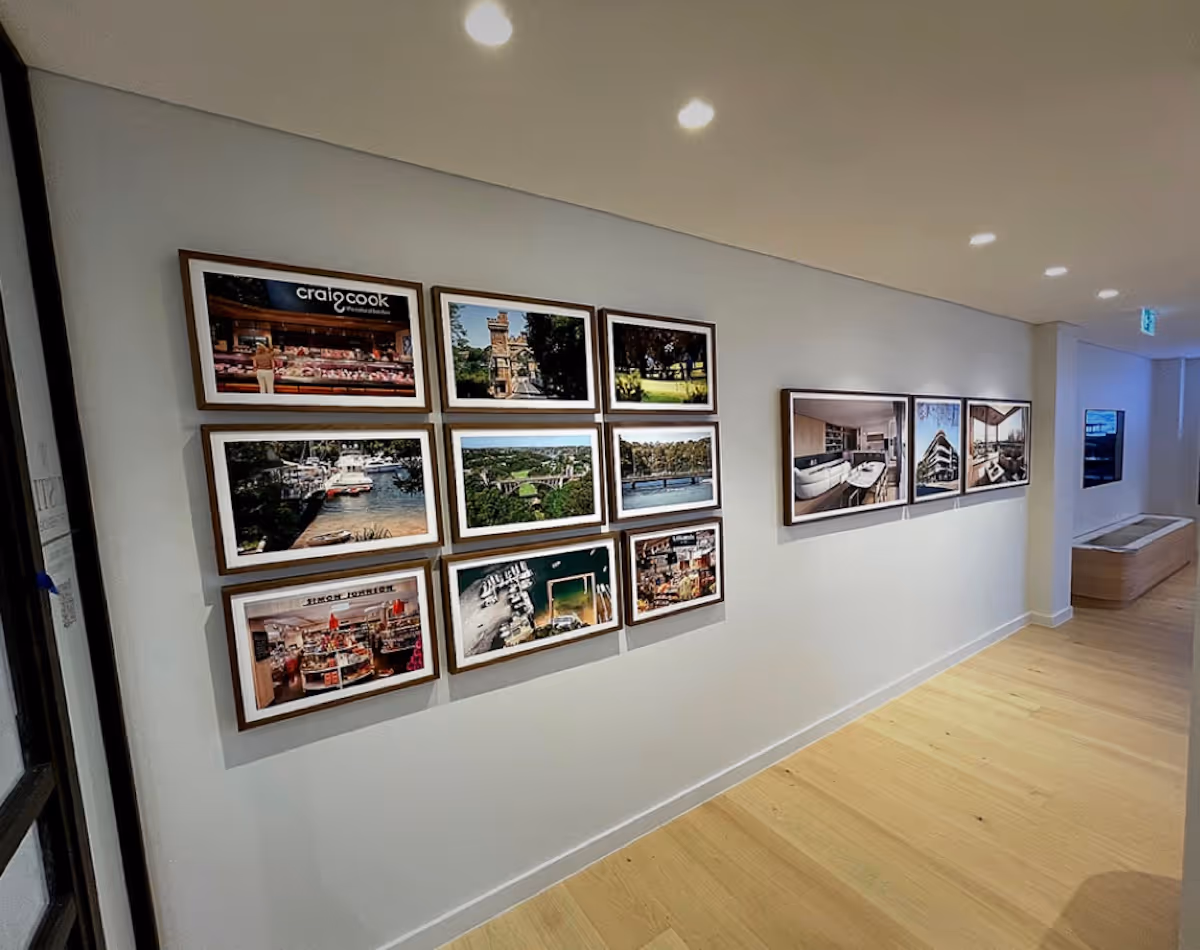 Gallery wall in a modern hallway with framed photos of landscapes, buildings, and interior spaces.