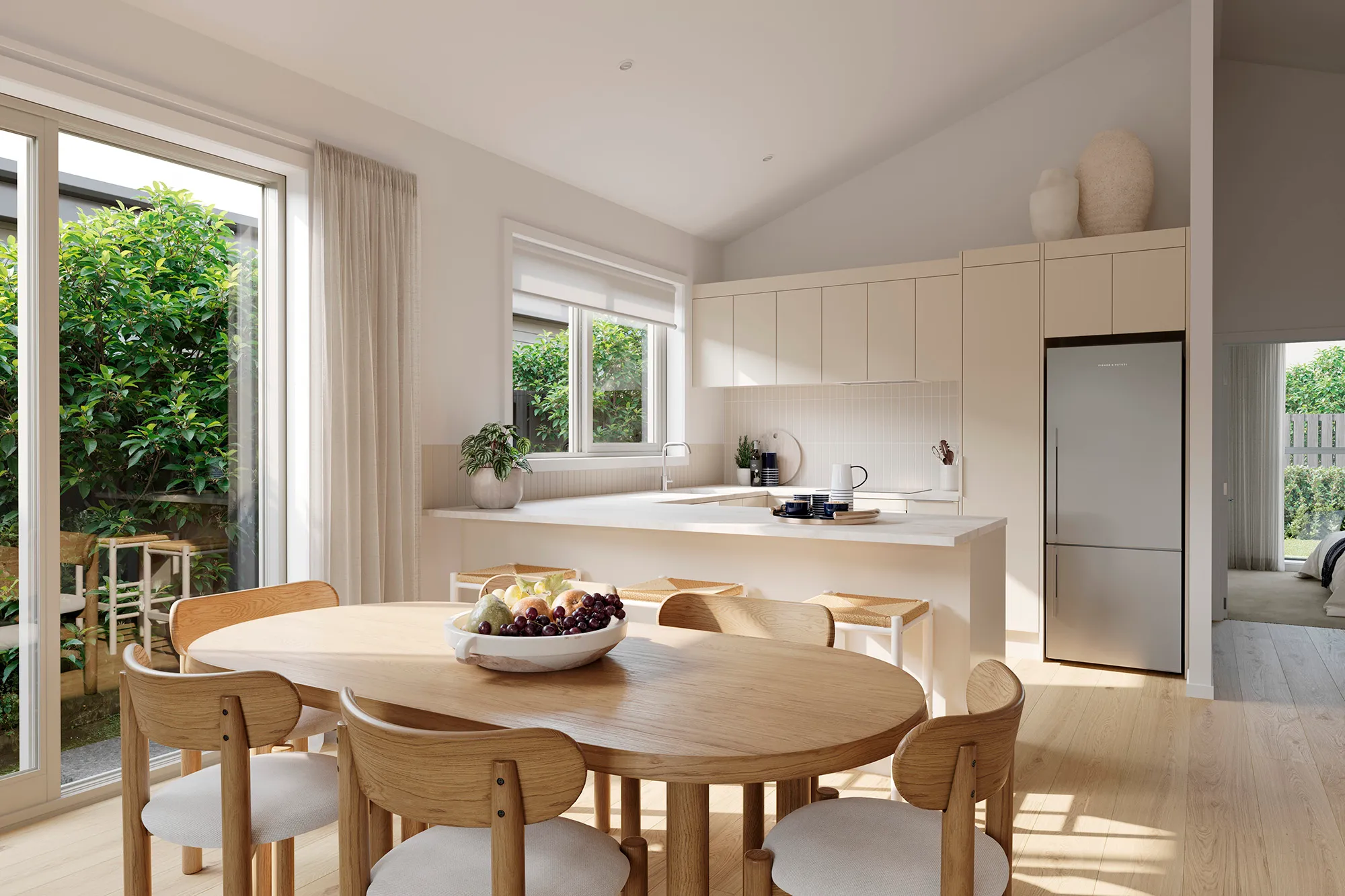 Bright modern kitchen and dining area with wooden oval table, six chairs, white countertops, and large windows overlooking greenery.