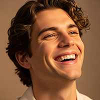 Smiling young man with curly brown hair looking upward against a brown background.