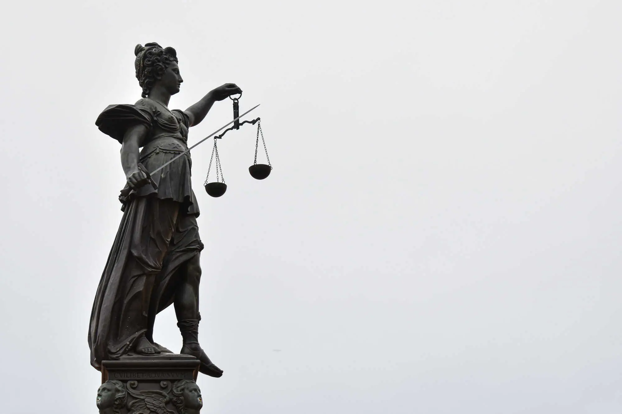Statue d'une figure féminine tenant une balance et une épée, symbolisant la justice.