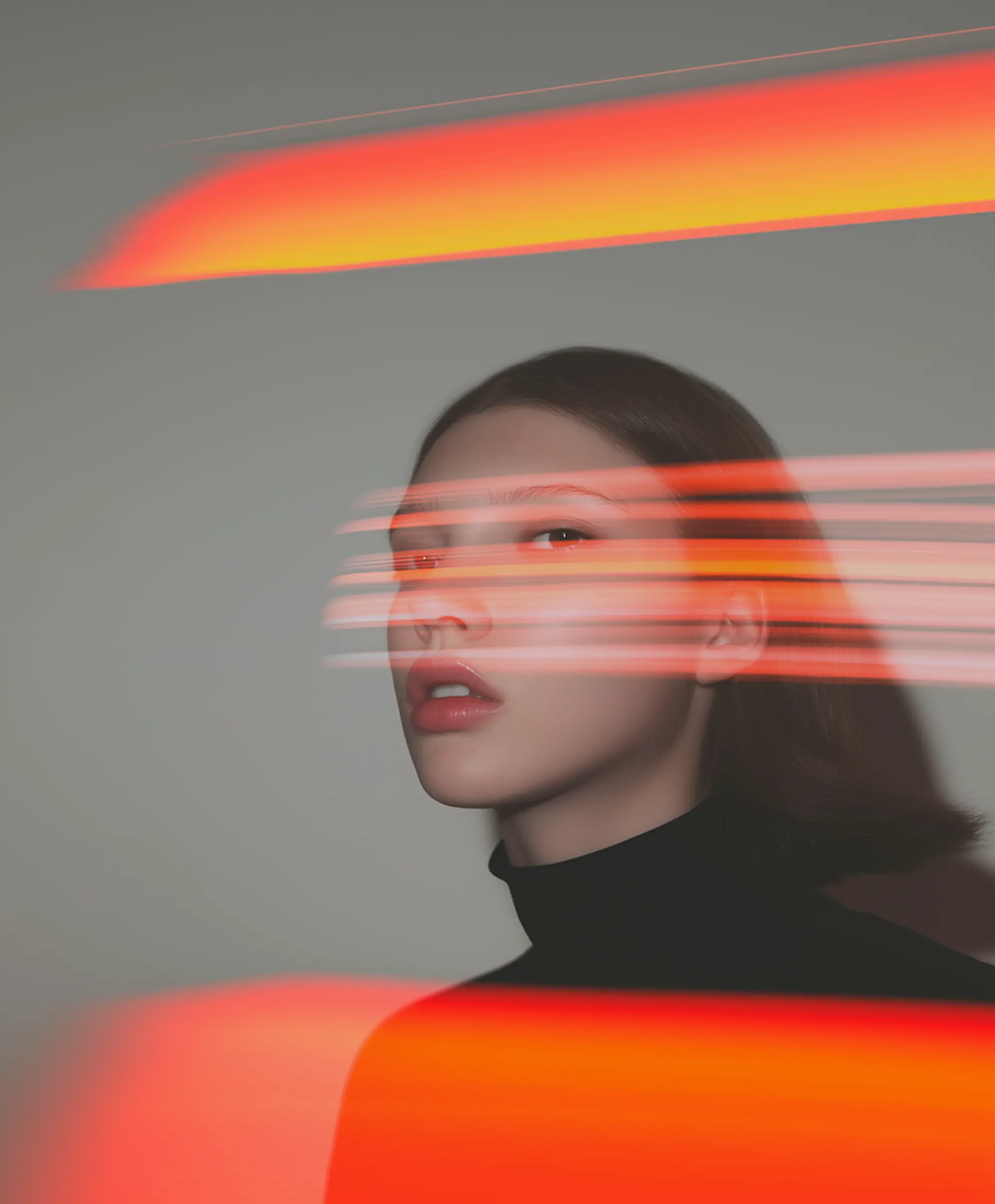 Portrait of a woman with short dark hair and red light streaks across her face and background.