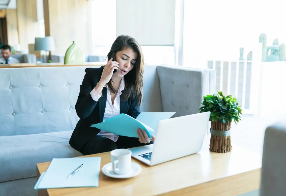 Une Sales Development Representative en train de passer un appel de prospection en étant assise sur un canapé