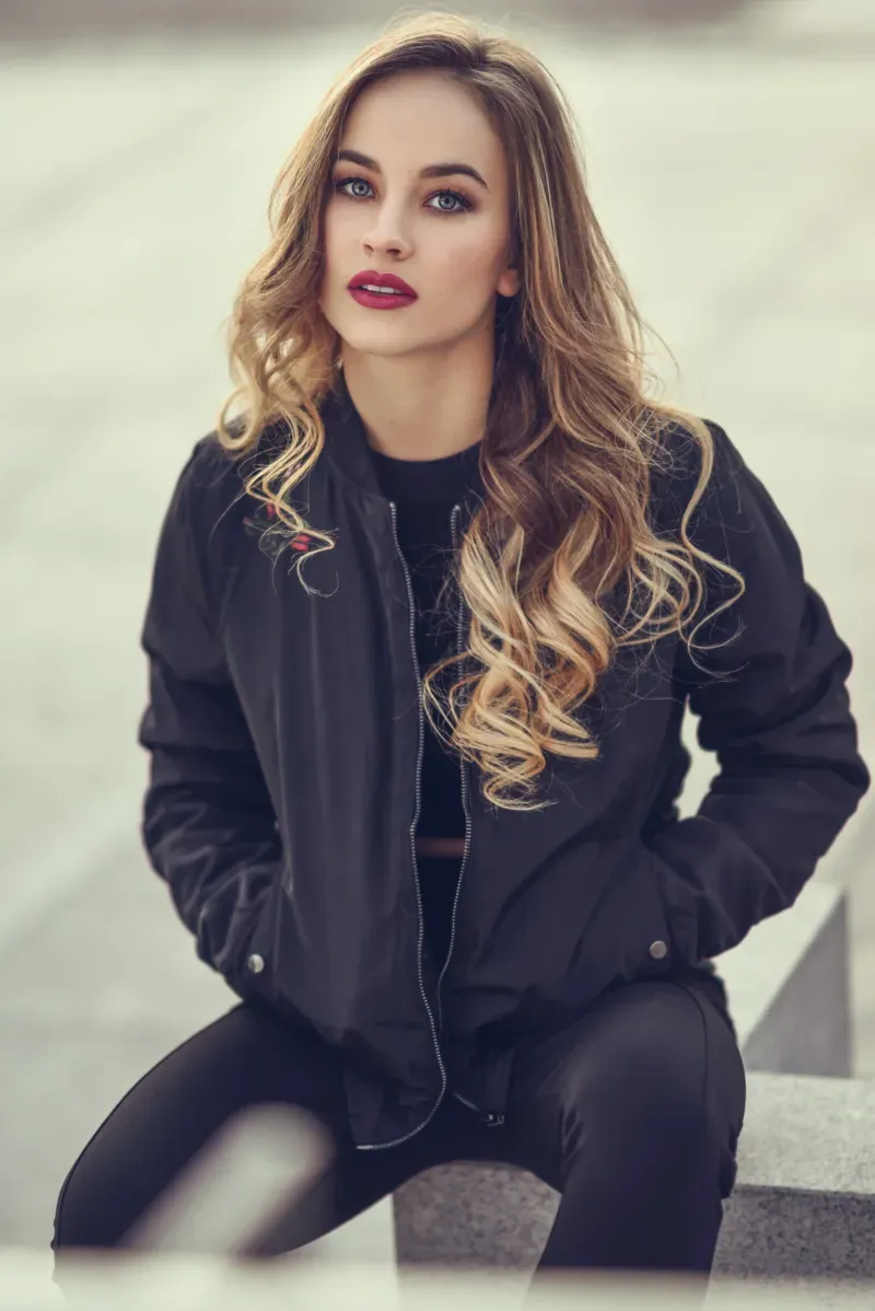 Model mit langen gewellten Haaren und schwarzer Bomberjacke im Portrait