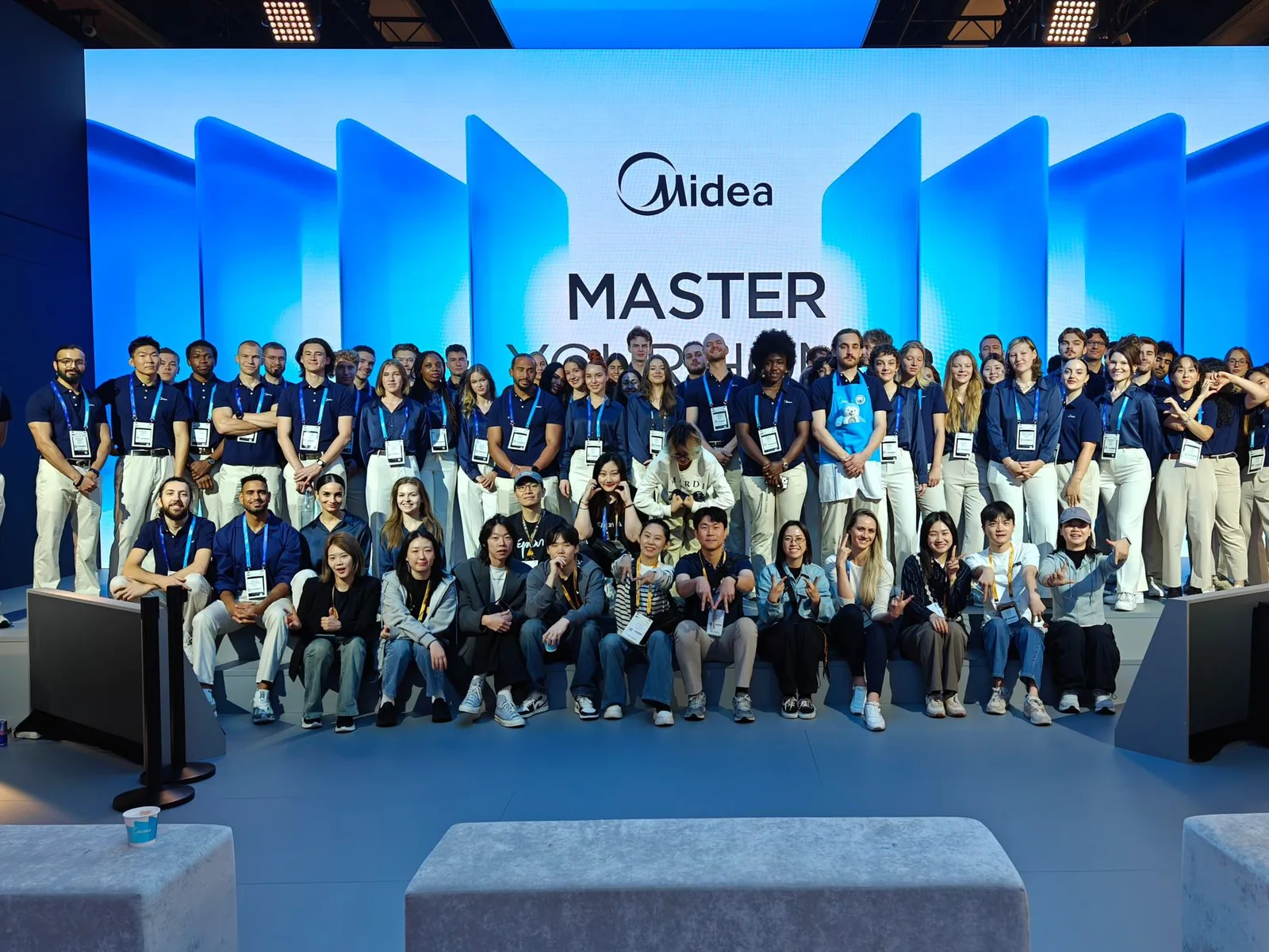 Das eventas-Team aus rund 100 Markenbotschaftern in Midea-Uniform vor der Midea-Bühnenwand auf der IFA 2025 in Berlin