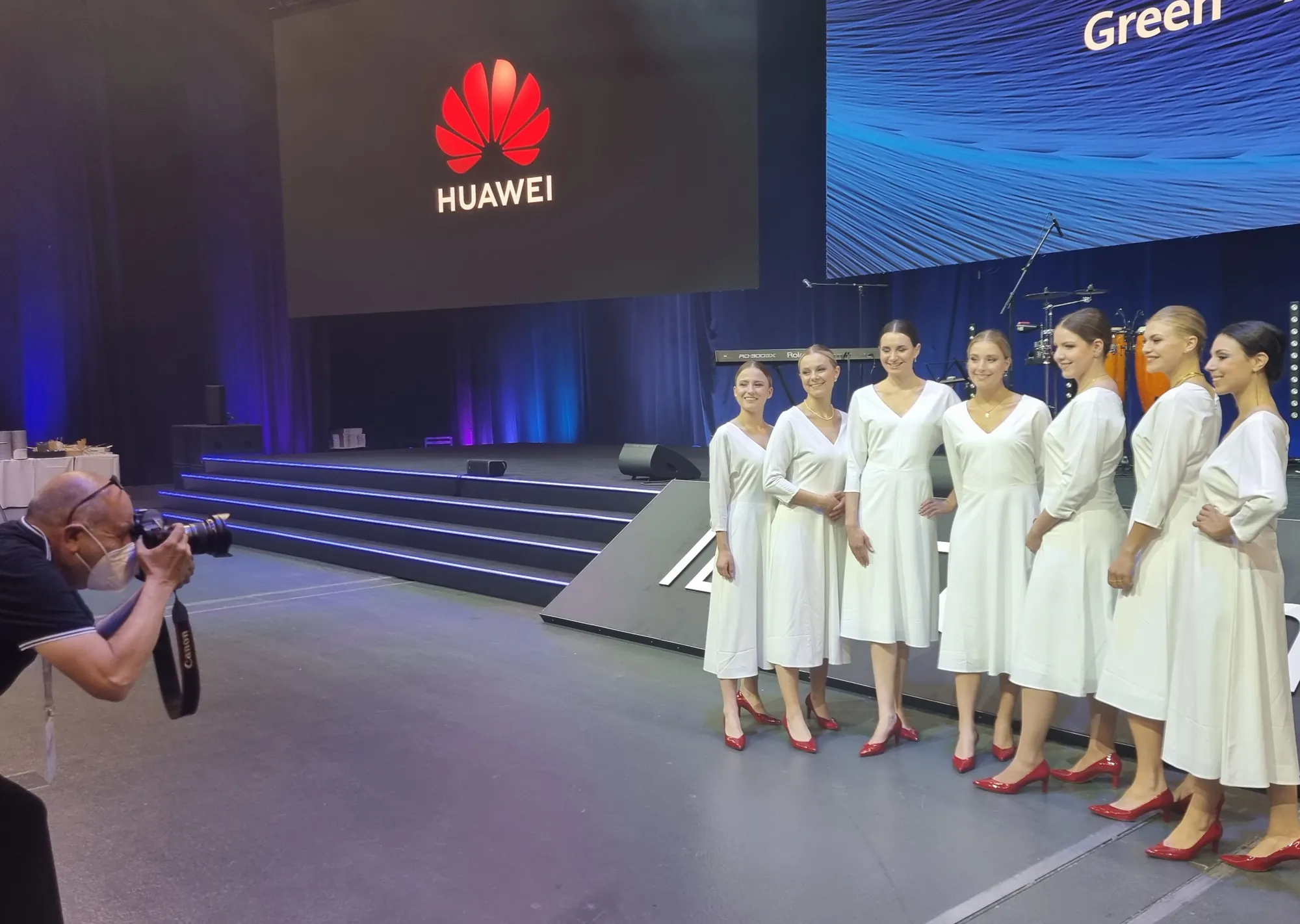 Photographer shooting the hostesses in white dresses on the stage of the Huawei IDI Forum 2022 | eventas