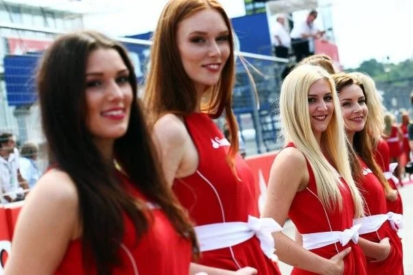 Four laughing grid girls in red Santander dresses with white bows at the 2014 German Grand Prix in Hockenheim