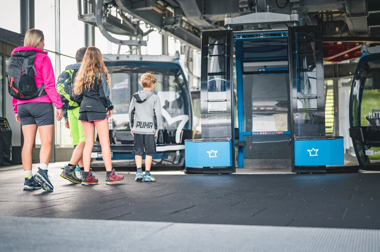 Family boarding a summer gondola at a Hochkönig cable car station in the Austrian Alps